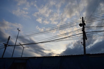 Low angle view of silhouette electricity pylon against sky