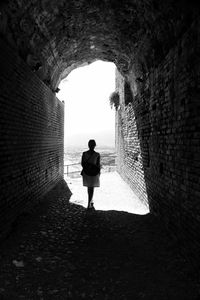 Rear view of woman standing in tunnel