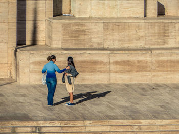 Friends standing on footpath against wall