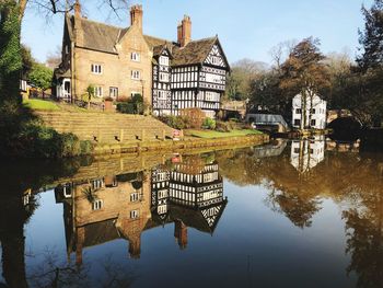 Built structure by lake and buildings against sky