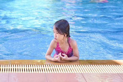 Little girl playing in outdoor swimming pool on summer vacation.
