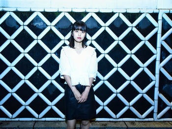 Portrait of young woman standing against built structure