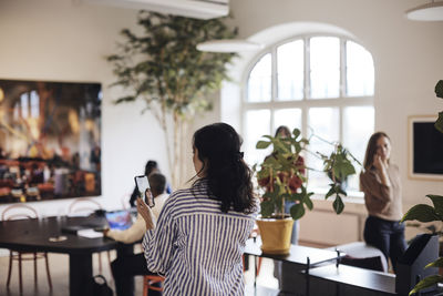 Rear view of businesswoman doing video call through smart phone at office