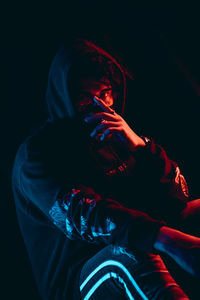 Portrait of man holding illuminated light against black background