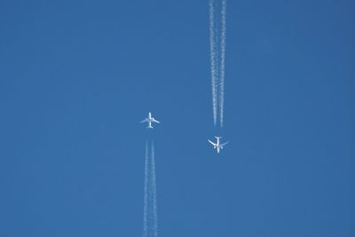 Low angle view of airplane flying against clear blue sky