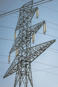 Low angle view of electricity pylon against clear blue sky