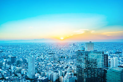 High angle view of illuminated city buildings against sky during sunset