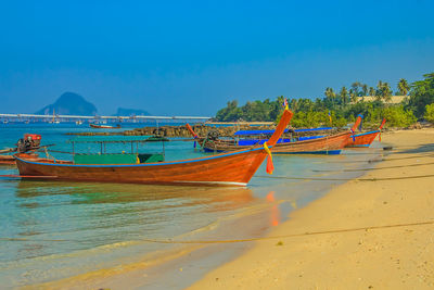 Boats in sea against clear blue sky