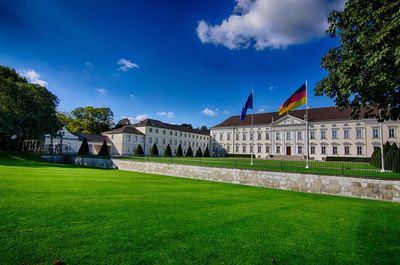 Flags in lawn by buildings against sky