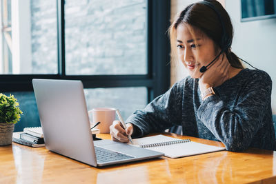Woman using mobile phone while sitting on table