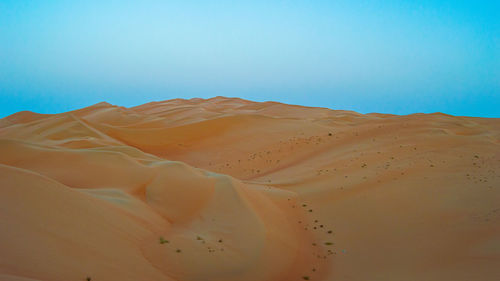 Scenic view of desert against clear blue sky