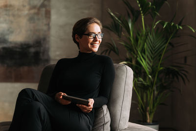 Young woman sitting against wall