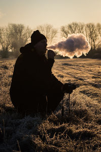 Silhouette of man smoking against sky during sunset
