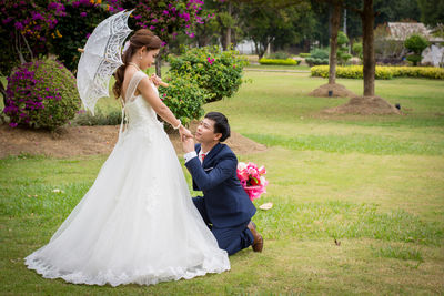 Side view of smiling young bride with groom romancing in park