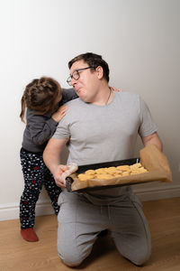 Father holding cookies in tray while talking to daughter