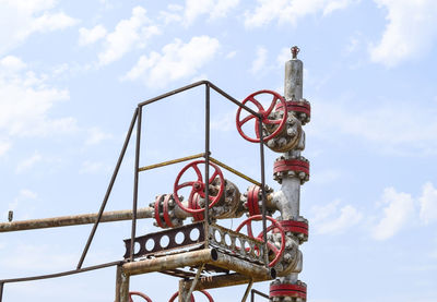 Low angle view of metallic machinery against sky