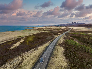 Endless road into the cloudy mountains and hills of iceland during sunny cloudy weather.