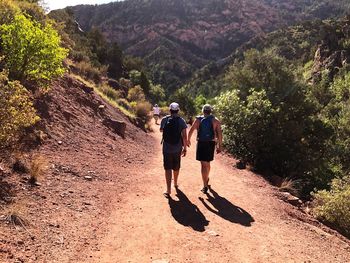 Rear view of friends walking on footpath leading towards mountain