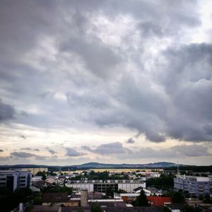 Buildings in town against cloudy sky