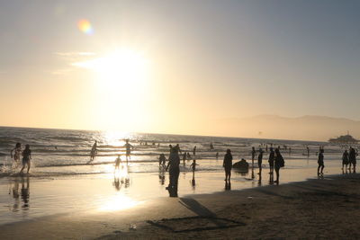 People on beach against sky during sunset