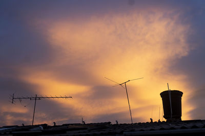 Silhouette cranes against sky during sunset