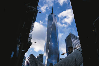 Low angle view of skyscrapers against cloudy sky