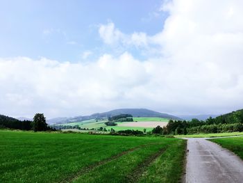 Road amidst field against sky