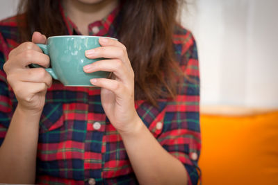 Midsection of woman holding coffee cup