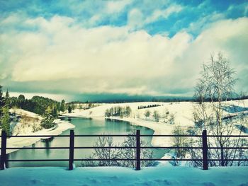 Snow covered landscape against cloudy sky