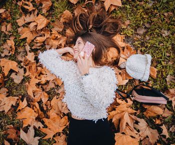 High angle view of woman with autumn leaves on field