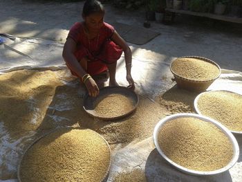 High angle view of woman cleaning grains on floor