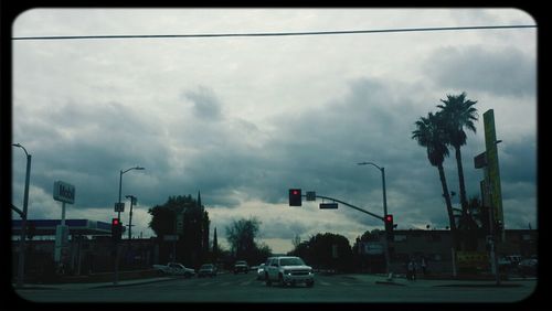 Traffic on road against cloudy sky