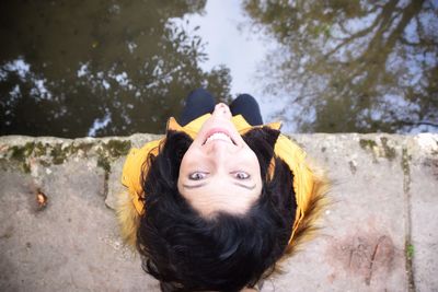 Portrait of woman sitting on pier over lake