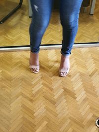 Low section of woman standing on hardwood floor at home
