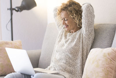 Young woman using laptop while sitting on sofa at home