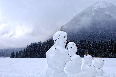 Snowman on field against cloudy sky