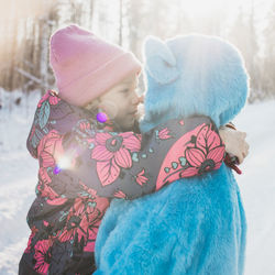 Father wearing costume with daughter on snowy field
