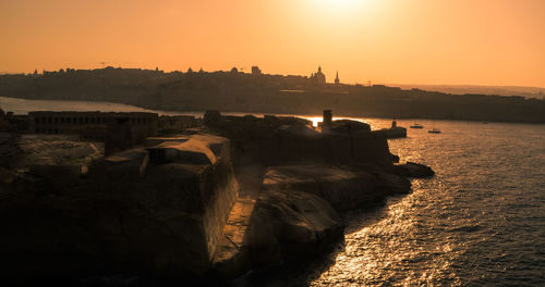 Scenic view of sea and buildings against sky during sunset