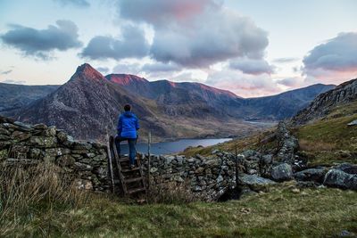 Rear view of man standing on mountain against sky