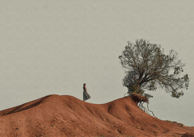 Full length of woman standing on sand dune against sky