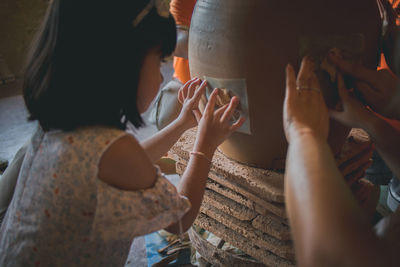 Side view of girl making floral pattern on pottery in workshop