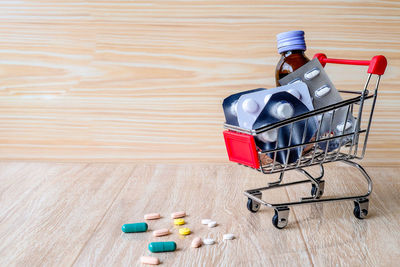 Medicines in toy shopping cart on wooden table