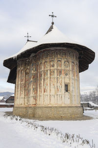 Traditional building on field against sky during winter