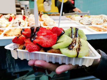 Close-up of hand holding fruit salad in plate