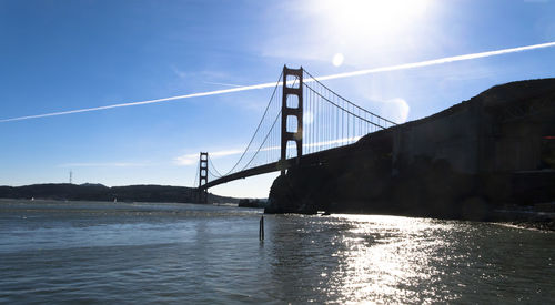 Golden gate bridge over sea against vapor trail in sky