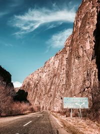 Road passing through rock formation against sky