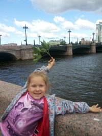 Portrait of smiling girl on river against sky
