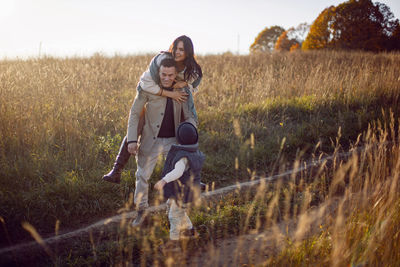 Stylish family with a boy child on a field in the dry grass in autumn