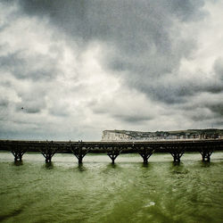 Bridge over river against cloudy sky