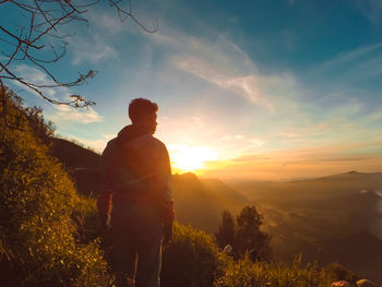 Man standing on field against sky during sunset